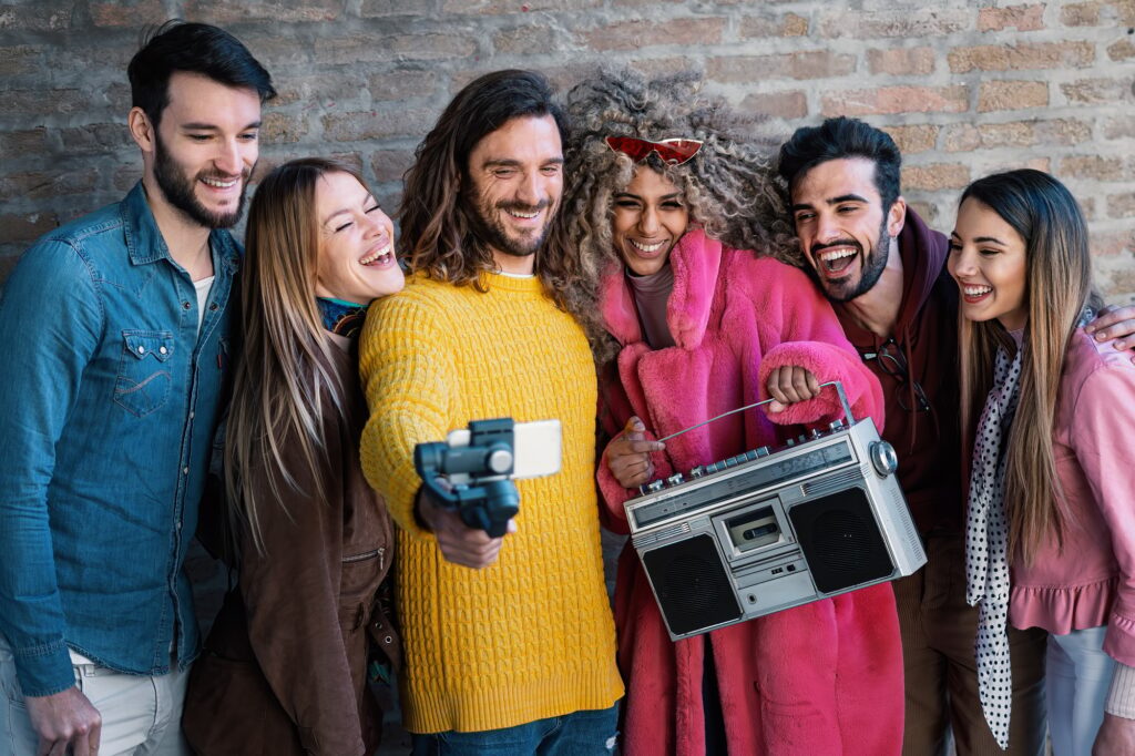 Group of friends laughing and filming a selfie video capturing fun moments with mobile gimbal